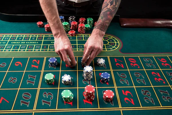 与轮盘赌的绿色赌场表的特写生动的形象, 用手的主持人和多彩多姿的芯片. — 图库照片