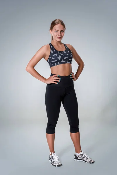 Brunette woman in black leggings, top and sneakers is posing isolated on  white. Fitness, gym, healthy lifestyle concept Stock Photo - Alamy