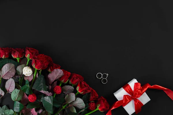 Κόκκινα τριαντάφυλλα, δαχτυλίδι και δώρο κουτί σε μαύρο φόντο — Φωτογραφία Αρχείου