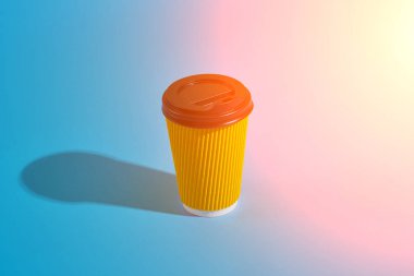 Mavi arka plan üzerinde siyah kapaklı sarı kağıt bardak sıcak kahve