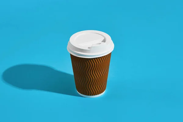 Café caliente en taza de papel marrón con tapa blanca sobre fondo azul — Foto de Stock