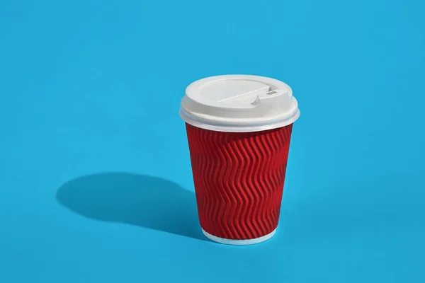 Café caliente en taza de papel rojo con tapa blanca sobre fondo azul wi — Foto de Stock