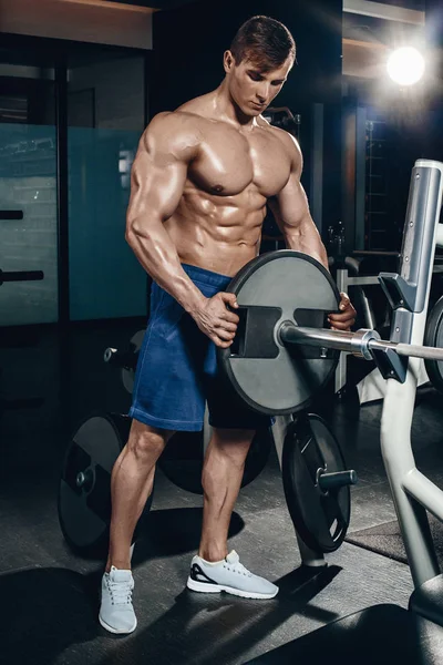 Knappe macht atletische man op dieet opleiding oppompen van spieren met dumbbell en barbell. Sterke bodybuilder, perfecte abs, schouders, biceps, triceps en borst — Stockfoto