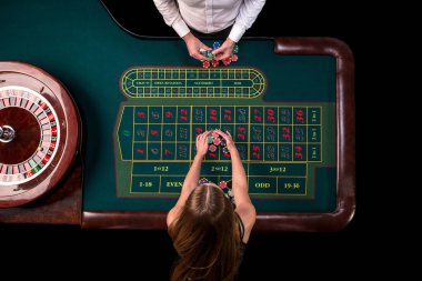 Adam krupiye ve tablo Casino Rulet oynayan kadın. Bir yeşil rulet masasında bir mezura ile Üstten Görünüm.