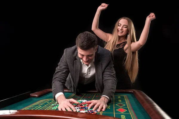 Young beautiful couple takes their winnings at the roulette table at the casino — Stock Photo, Image