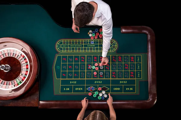 Krupiér muž a žena u stolu v kasinu hrát ruletu. Pohled shora u stolu rulety zelené s páskou opatření. — Stock fotografie