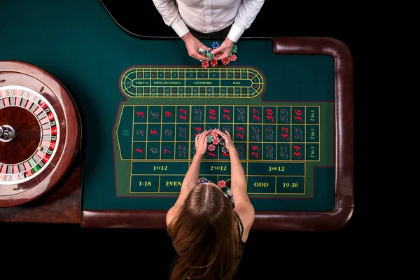 Man croupier and woman playing roulette at the table in the casino. Top view at a roulette green table with a tape measure. — Stock Photo, Image