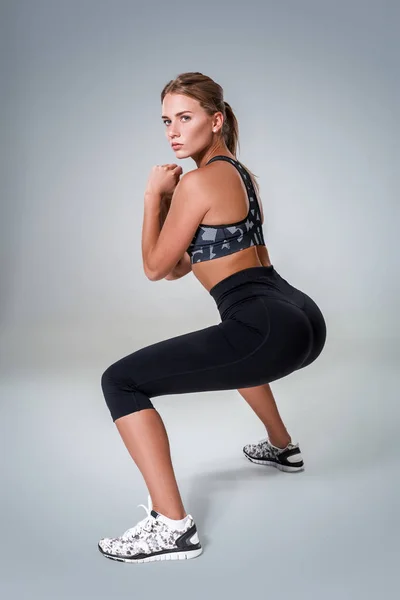 Mulher fitness em roupas esportivas fazendo sit-ups, tiro estúdio — Fotografia de Stock