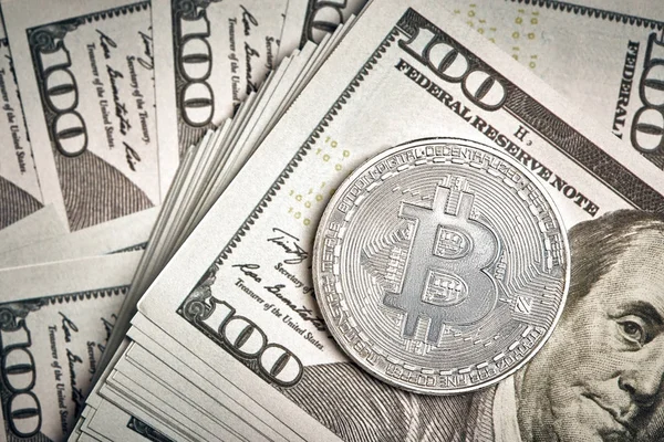 100 dolarlık banknotların üzerinde Bitcoin 'in sembolik sikkeleri. Bitcoin 'i bir dolara değişelim..