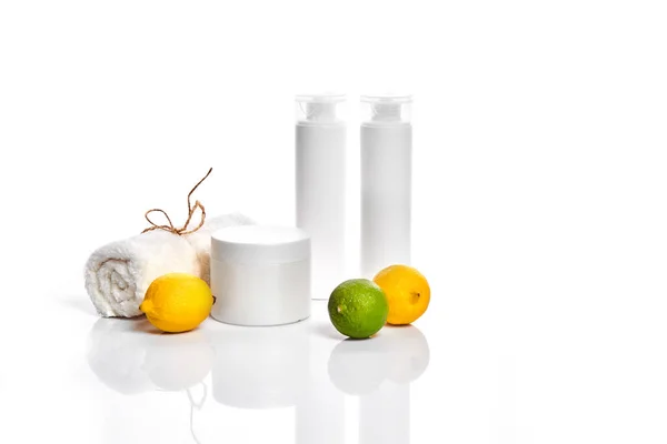 白瓶和两个整体柠檬和石灰隔离在白色背景。广告化妆品的概念 — 图库照片