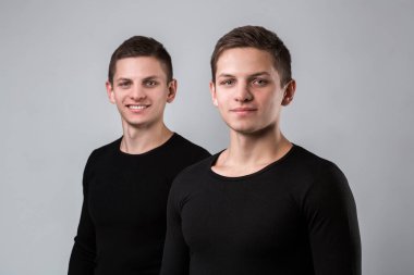 İki ikiz kardeşi stand gri arka plan üzerinde