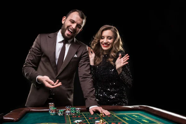 Man and woman playing at roulette table in casino