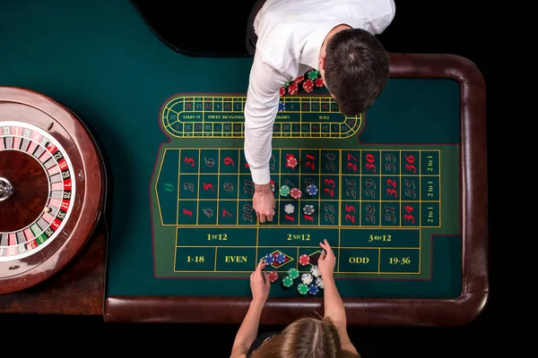 Hombre croupier y mujer jugando a la ruleta en la mesa en el casino. Vista superior en una mesa verde de ruleta con una cinta métrica . — Foto de Stock