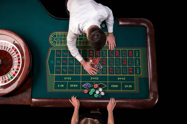 Homme croupier et femme jouant à la roulette à la table dans le casino. Vue de dessus à une table de roulette verte avec un mètre ruban . — Photo