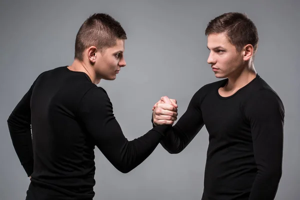 Portrait de jeunes frères jumeaux debout face à face sur ba gris — Photo