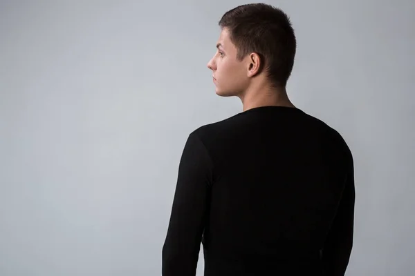 Achteraanzicht van de mens in zwarte trui. Permanent jonge kerel. Achteraanzicht — Stockfoto