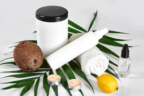 Кокос з баночками кокосової олії та косметичним кремом на білому тлі — стокове фото