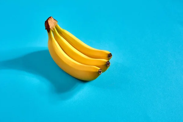 Yellow ripe bananas on blue background with space for text or design. Top view — Stock Photo, Image