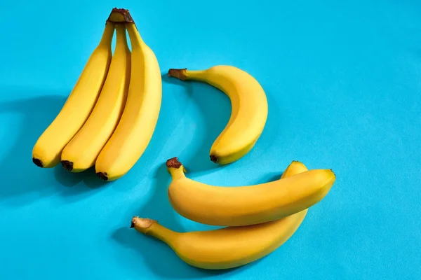 Gelbe reife Bananen auf blauem Hintergrund mit Platz für Text oder Design. Ansicht von oben — Stockfoto