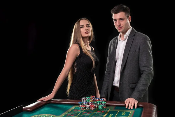 Elegante pareja en el casino apostando por la ruleta, sobre un fondo negro — Foto de Stock