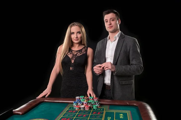 Élégant couple au casino pariant sur la roulette, sur fond noir — Photo