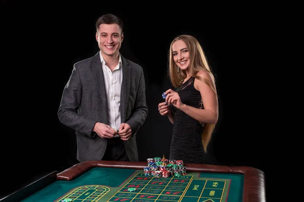 黒の背景に、ルーレットに賭けるカジノでエレガントなカップル — ストック写真