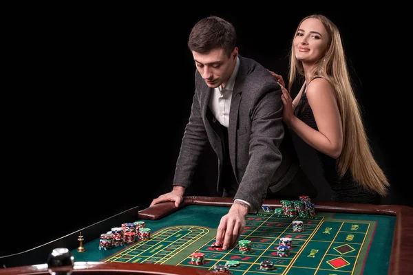 优雅的情侣在赌场投注轮盘赌, 在黑色背景 — 图库照片