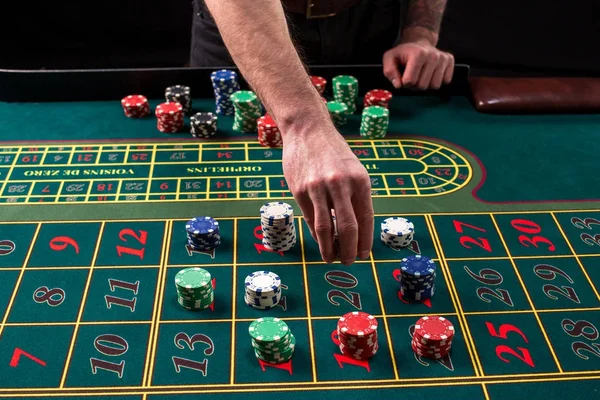 Une image animée en gros plan de table de casino verte avec roulette, avec les mains de croupier et de jetons multicolores . — Photo