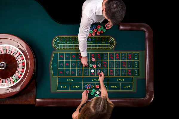 Hombre croupier y mujer jugando a la ruleta en la mesa en el casino. Vista superior en una mesa verde de ruleta con una cinta métrica . —  Fotos de Stock