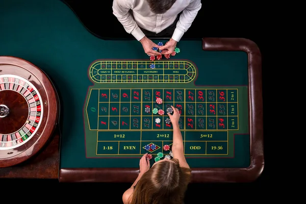 Uomo croupier e donna che giocano alla roulette al tavolo del casinò. Vista dall'alto a un tavolo verde roulette con un metro a nastro . — Foto Stock