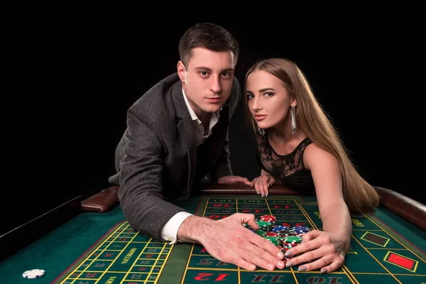 Joven hermosa pareja toma sus ganancias en la mesa de ruleta en el casino —  Fotos de Stock