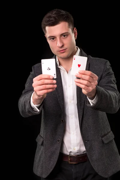 Кавказький юнак носити костюм виявиться два тузи в його руках на чорному тлі. Азартні ігри концепції. Казино — стокове фото