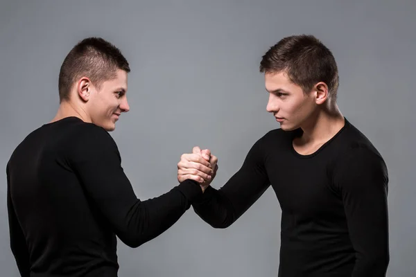 Retrato de jovens irmãos gêmeos de pé face a face em cinza ba — Fotografia de Stock