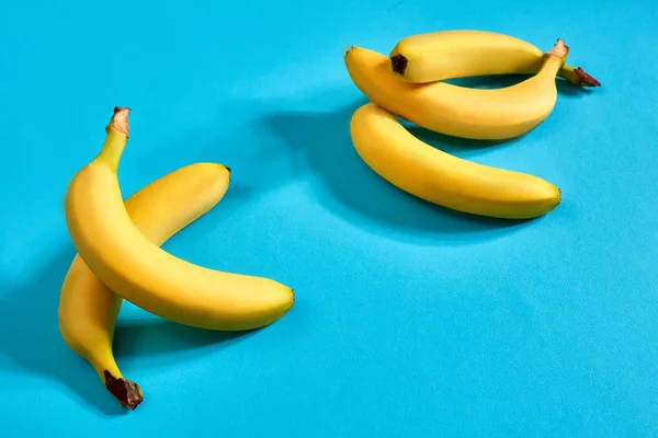 Banane fresche da vicino su sfondo blu brillante. Piatto. Concetto estivo . — Foto Stock