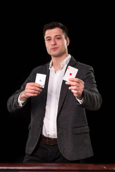 Unga kaukasiska man klädd i kostym som håller två ess i händerna på svart bakgrund. Gambling koncept. Casino — Stockfoto