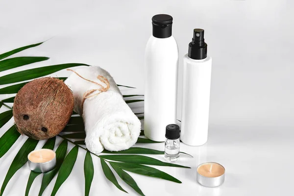 Кокос з баночками кокосової олії та косметичним кремом на білому тлі — стокове фото