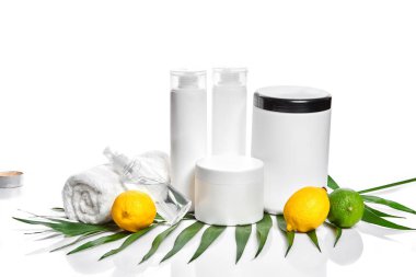 White bottles and two whole lemon and lime isolated on white background. The concept for advertising cosmetics clipart