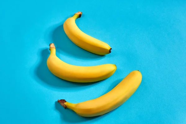 Frische Bananen aus nächster Nähe auf hellblauem Hintergrund. flach lag. Sommerkonzept. — Stockfoto