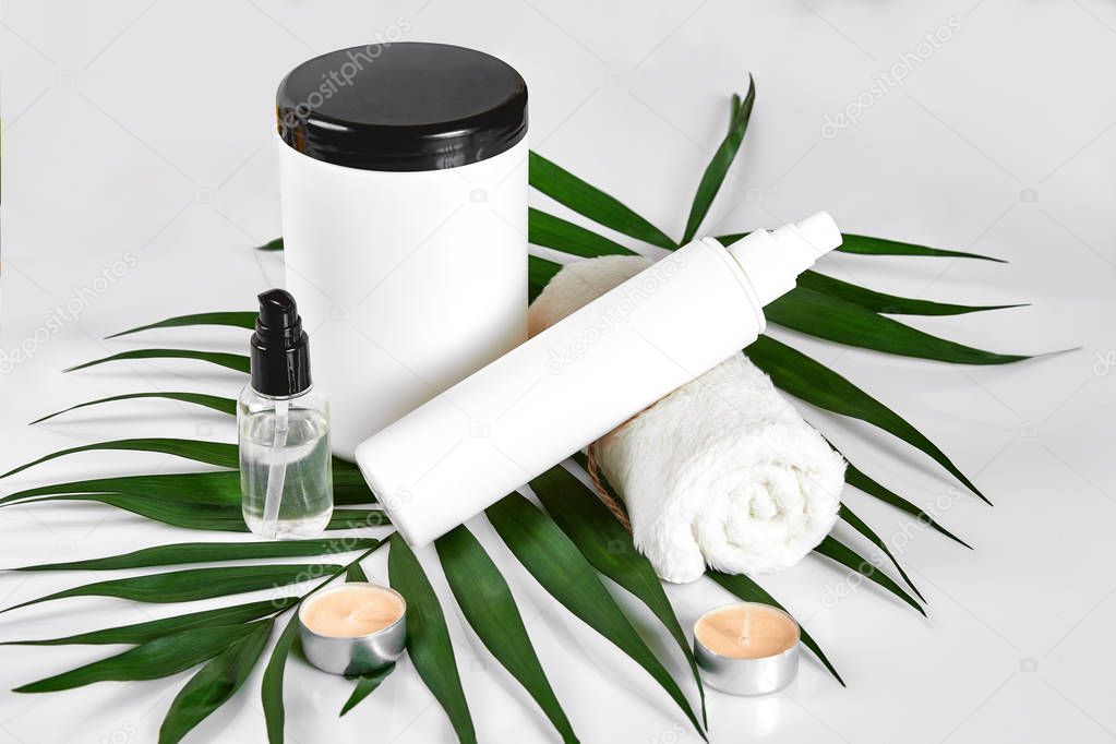 White cosmetic products and green leaf on white background. Natural beauty products for branding mock-up concept.