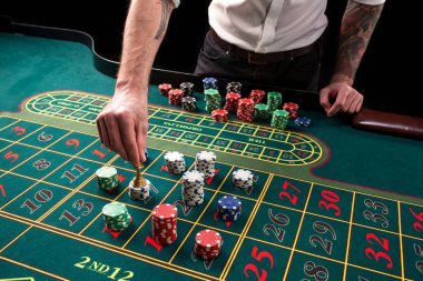 Yeşil casino rulet, krupiye ve çok renkli fiş elleriyle tabloyla bir yakın çekim canlı görüntüsünü.