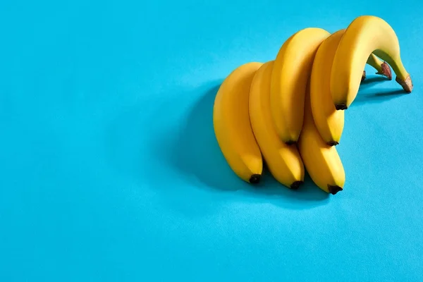 Banane fresche da vicino su sfondo blu brillante. Piatto. Concetto estivo . — Foto Stock