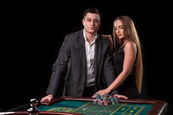 Élégant couple au casino pariant sur la roulette, sur fond noir — Photo