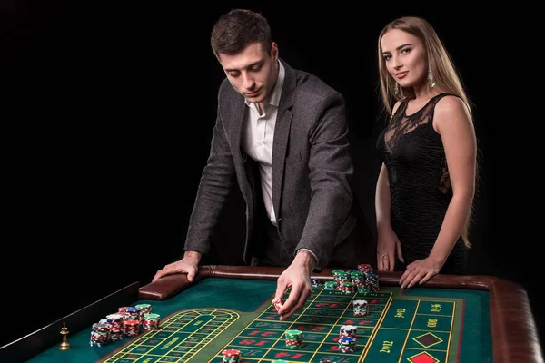 Elegantní pár v kasinu sázení na ruletu, na černém pozadí — Stock fotografie