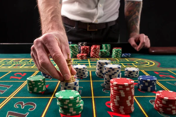 Una imagen vibrante de primer plano de la mesa de casino verde con ruleta, con las manos de croupier y fichas multicolores . — Foto de Stock
