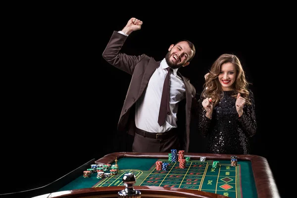 Man and woman playing at roulette table in casino