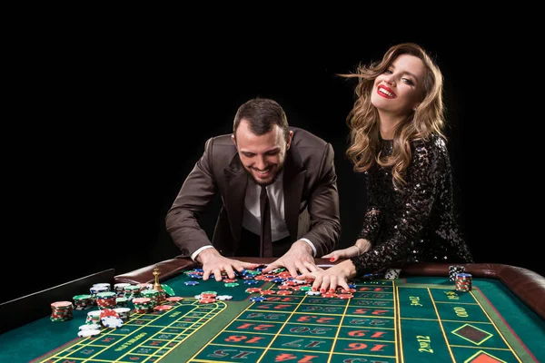 Man and woman playing at roulette table in casino