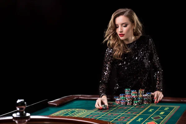 Woman playing in casino. Woman stakes piles of chips playing rou