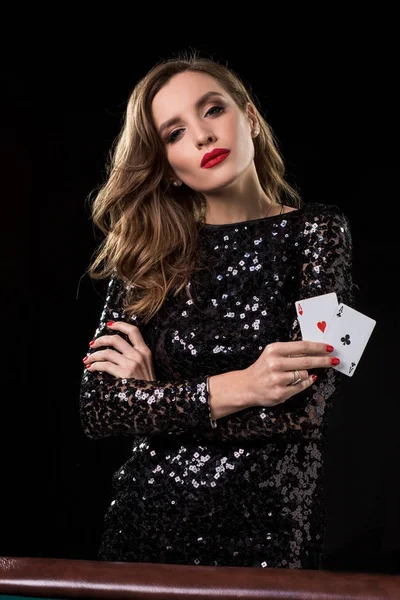 Young woman holding playing cards against a black background