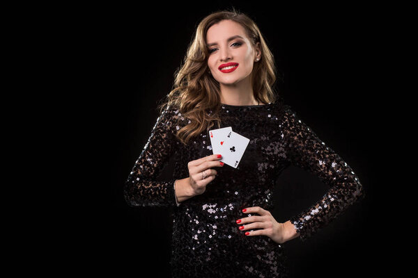 Young woman holding playing cards against a black background