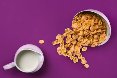 Bir kase mısır gevreği, süt mor arka planda, üstten görünüm sürahi